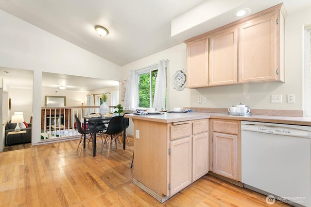 kitchen featuring white dishwasher, light countertops, light brown cabinets, a peninsula, and lofted ceiling