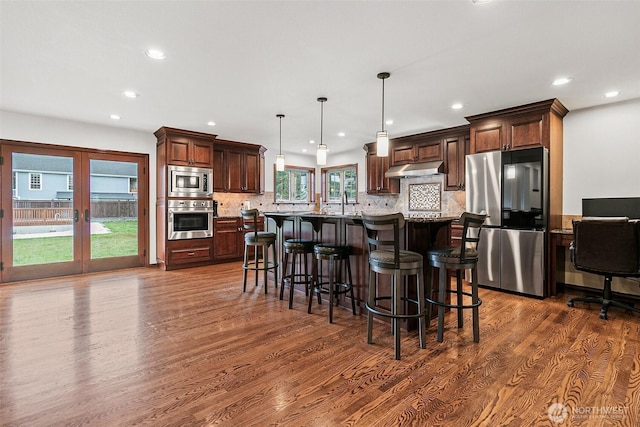 16915 32nd Ave E, Tacoma, WA 98446 - kitchen featuring appliances with stainless steel finishes, dark wood-type flooring, under cabinet range hood, recessed lighting, and a breakfast bar area