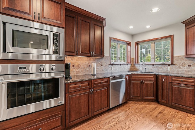 16915 32nd Ave E, Tacoma, WA 98446 - kitchen featuring appliances with stainless steel finishes, a sink, light wood finished floors, dark stone countertops, and recessed lighting