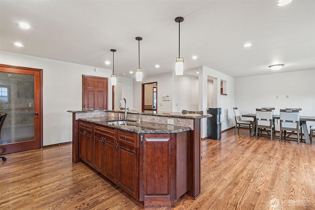 16915 32nd Ave E, Tacoma, WA 98446 - kitchen with a sink, light wood-type flooring, a kitchen island with sink, recessed lighting, and dark stone countertops