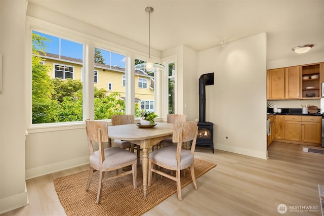 120 Hall Brothers Loop NW Unit 103, Bainbridge Island, WA 98110 - dining space featuring healthy amount of natural light, a wood stove, baseboards, and light wood-style floors