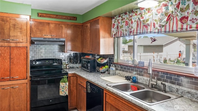 1102 E Elm St, Othello, WA 99344 - kitchen with black appliances, a sink, under cabinet range hood, brown cabinets, and tasteful backsplash