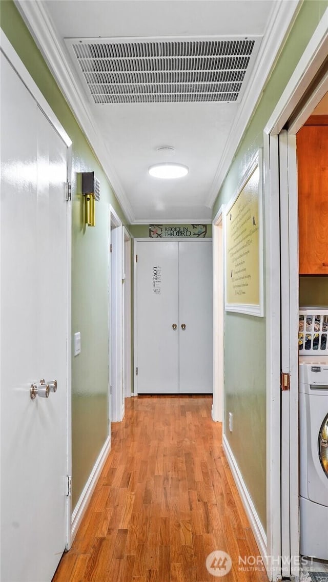 1102 E Elm St, Othello, WA 99344 - corridor with washer / dryer, ornamental molding, wood finished floors, and baseboards