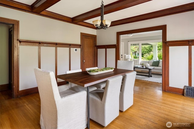 dining room with light wood-style flooring, beam ceiling, and a chandelier