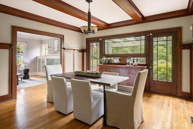 dining space featuring a chandelier, light wood-type flooring, plenty of natural light, crown molding, and beamed ceiling