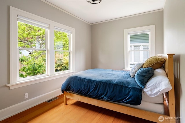 bedroom featuring baseboards, wood finished floors, and crown molding