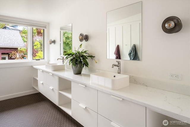 full bath with double vanity and baseboards