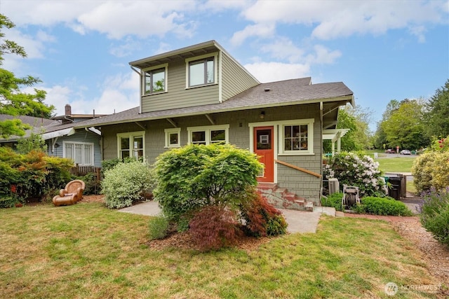 view of front facade featuring entry steps, a front yard, and a shingled roof