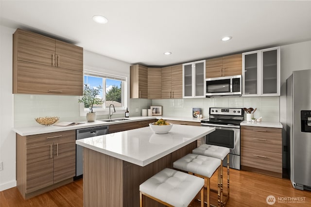 5903 19th Ave S, Seattle, WA 98108 - kitchen with stainless steel appliances, a breakfast bar, brown cabinets, glass insert cabinets, and wood finished floors
