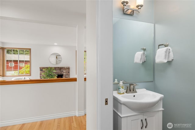 8484 NE County Park Rd, Bainbridge Island, WA 98110 - bathroom featuring wood finished floors, vanity, a brick fireplace, and baseboards