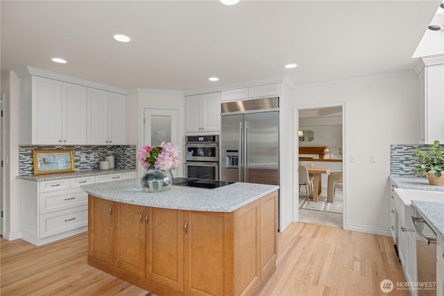 8484 NE County Park Rd, Bainbridge Island, WA 98110 - kitchen featuring stainless steel appliances, a center island, light wood finished floors, tasteful backsplash, and white cabinetry
