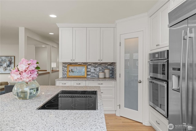 8484 NE County Park Rd, Bainbridge Island, WA 98110 - kitchen featuring appliances with stainless steel finishes, white cabinetry, light stone countertops, light wood finished floors, and recessed lighting