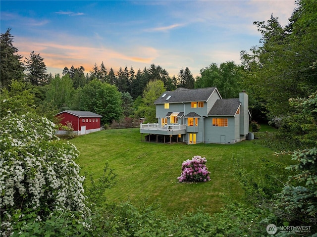 8484 NE County Park Rd, Bainbridge Island, WA 98110 - rear view of house featuring a chimney, a wooden deck, a lawn, and a detached garage