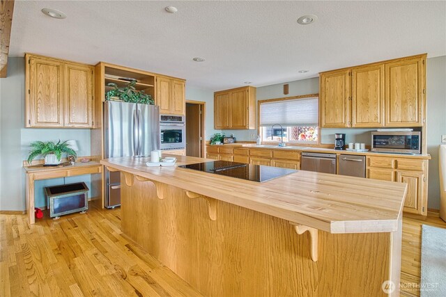 4020 Mayne Ln, Ferndale, WA 98248 - kitchen with appliances with stainless steel finishes, a sink, light wood-style floors, a kitchen breakfast bar, and open shelves