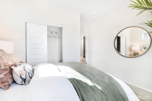 carpeted bedroom featuring a closet and baseboards