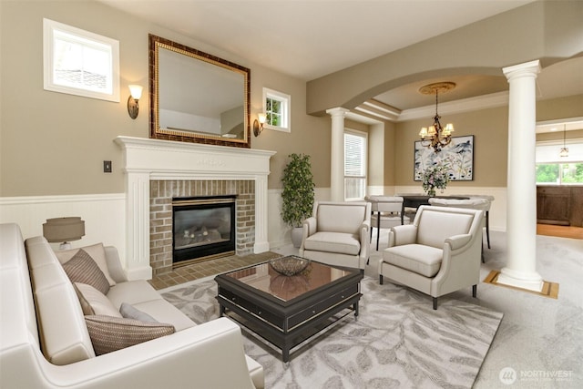 3612 Spyglass Dr NE, Tacoma, WA 98422 - carpeted living room featuring ornate columns, a chandelier, wainscoting, a fireplace, and arched walkways
