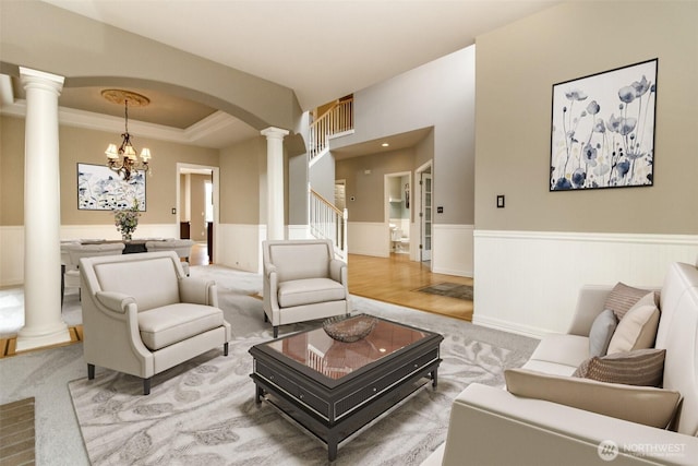 3612 Spyglass Dr NE, Tacoma, WA 98422 - living room featuring ornate columns, a wainscoted wall, arched walkways, a raised ceiling, and a chandelier