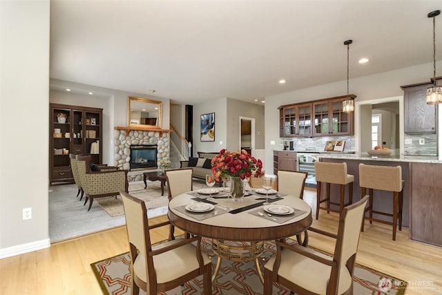 3612 Spyglass Dr NE, Tacoma, WA 98422 - dining area featuring a fireplace, light wood-style flooring, recessed lighting, and baseboards