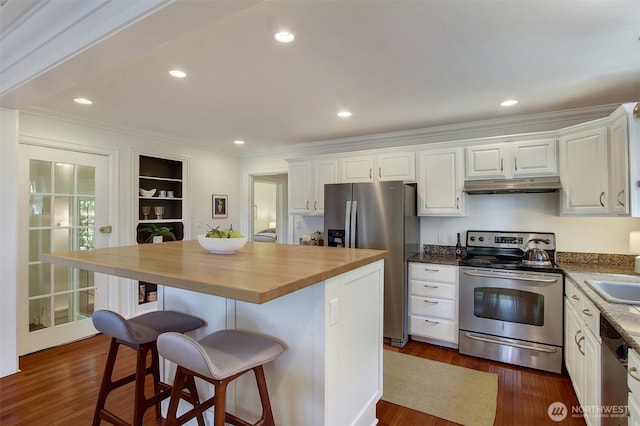 7508 13th Ave SW, Seattle, WA 98106 - kitchen with appliances with stainless steel finishes, under cabinet range hood, wooden counters, white cabinets, and a breakfast bar