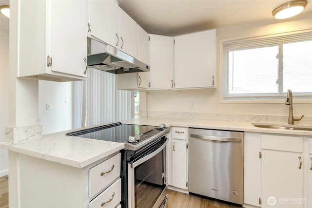kitchen featuring appliances with stainless steel finishes, a sink, under cabinet range hood, light wood-style floors, and white cabinetry