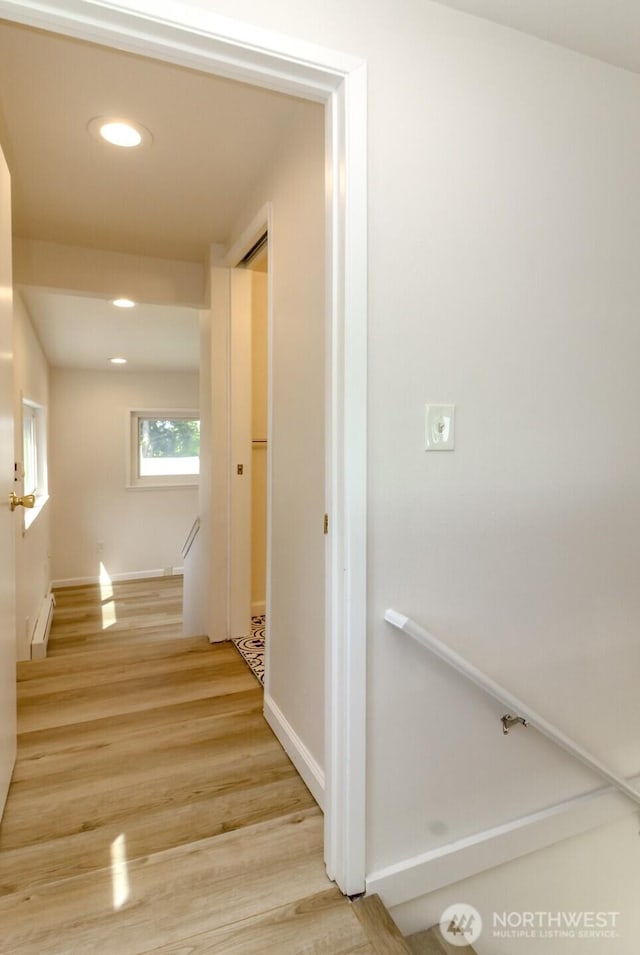 corridor with baseboard heating, an upstairs landing, light wood-style floors, baseboards, and recessed lighting