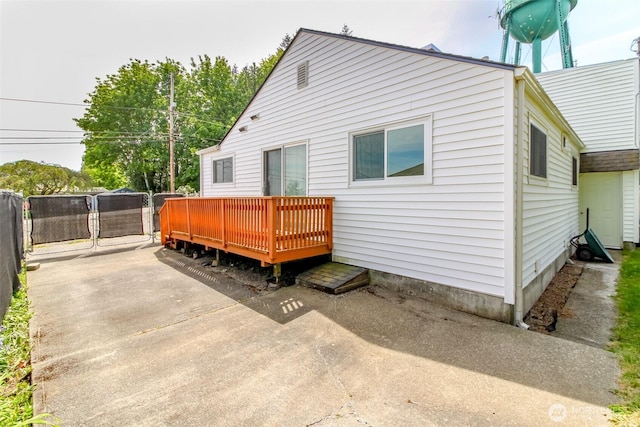 rear view of property featuring a wooden deck, fence, and a patio