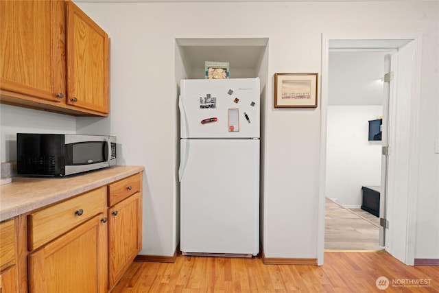 2019 Joe Johns Rd, Ocean Park, WA 98640 - kitchen featuring freestanding refrigerator, stainless steel microwave, light countertops, and light wood-style flooring