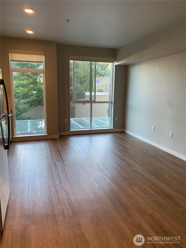 unfurnished room featuring wood finished floors, baseboards, and recessed lighting