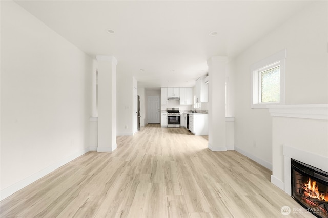 320 Kearney St, Centralia, WA 98531 - unfurnished living room with light wood finished floors, a warm lit fireplace, and baseboards