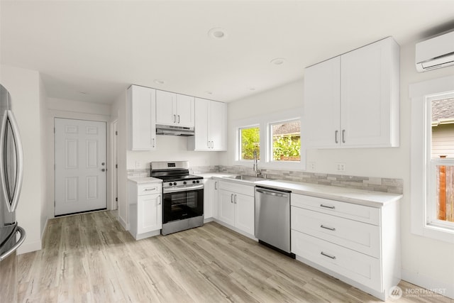 320 Kearney St, Centralia, WA 98531 - kitchen featuring stainless steel appliances, a sink, under cabinet range hood, an AC wall unit, and white cabinets