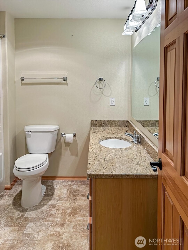 510 Oregon Ave N, Long Beach, WA 98631 - bathroom with vanity, toilet, stone finish flooring, and baseboards