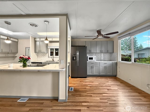 18425 NE 95th St Unit 8, Redmond, WA 98052 - kitchen with stainless steel fridge, gray cabinets, white microwave, a ceiling fan, and decorative backsplash