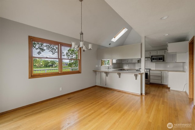 187 Acorn, Longview, WA 98632 - kitchen featuring appliances with stainless steel finishes, a peninsula, a skylight, a chandelier, and a breakfast bar area