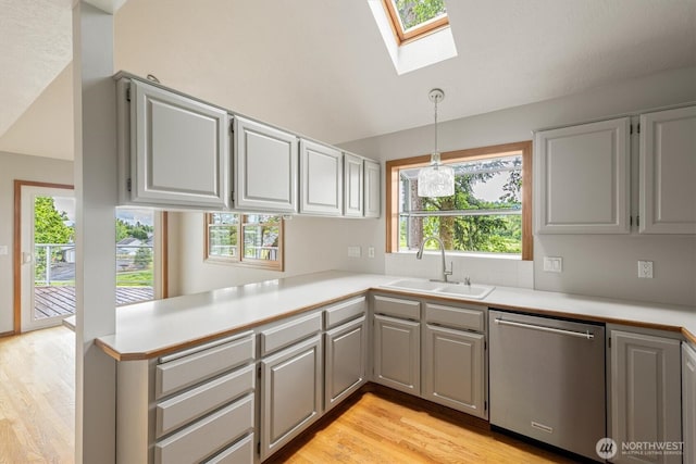 187 Acorn, Longview, WA 98632 - kitchen with stainless steel dishwasher, a skylight, a sink, light wood-style flooring, and light countertops