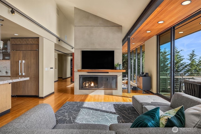 7703 W Mercer Way, Mercer Island, WA 98040 - living area with wood finished floors, a warm lit fireplace, recessed lighting, and a wall of windows