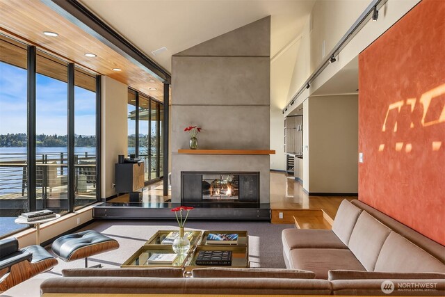 7703 W Mercer Way, Mercer Island, WA 98040 - living area featuring a towering ceiling, a water view, a multi sided fireplace, and recessed lighting
