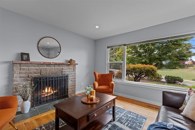 living room with a fireplace with flush hearth, plenty of natural light, baseboards, wood finished floors, and recessed lighting