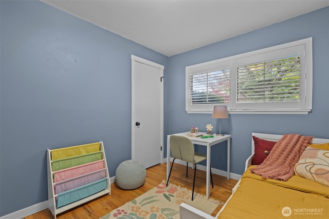 bedroom with wood finished floors, baseboards, and a closet