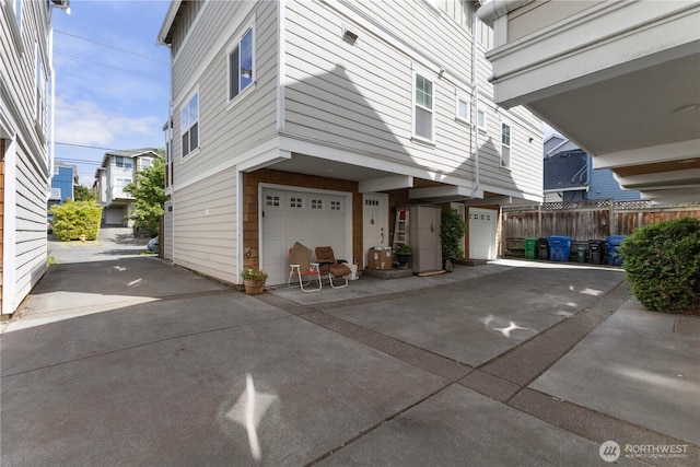 view of side of home with a garage, driveway, and fence