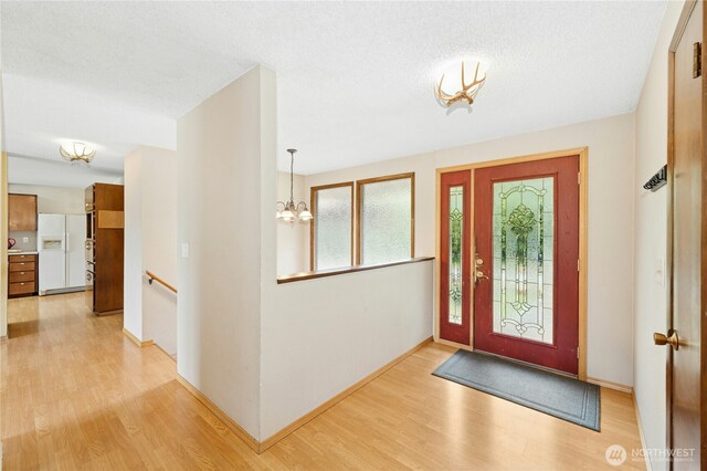 10410 260th St E, Graham, WA 98338 - entrance foyer featuring light wood-style flooring, a chandelier, baseboards, and a textured ceiling