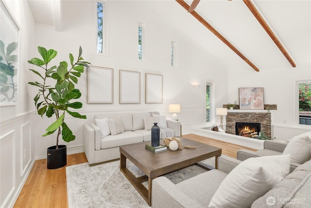 464 7th Ave, Fox Island, WA 98333 - living room featuring wood finished floors, beam ceiling, a stone fireplace, and high vaulted ceiling
