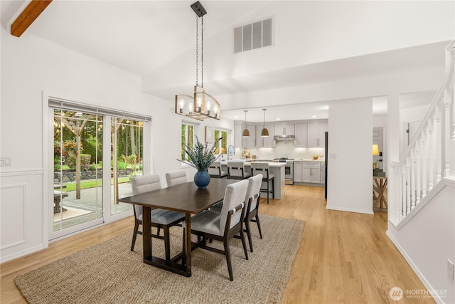 464 7th Ave, Fox Island, WA 98333 - dining area with light wood finished floors, a chandelier, stairway, high vaulted ceiling, and beam ceiling