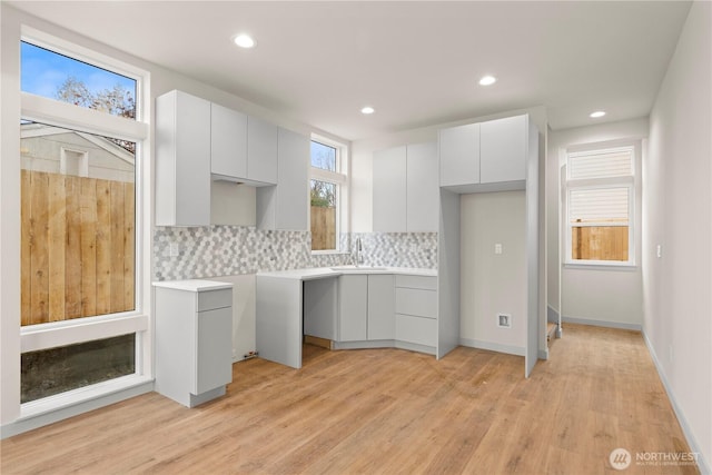 5517A 9th Ave NW, Seattle, WA 98107 - kitchen featuring modern cabinets, a sink, backsplash, light wood-type flooring, and recessed lighting