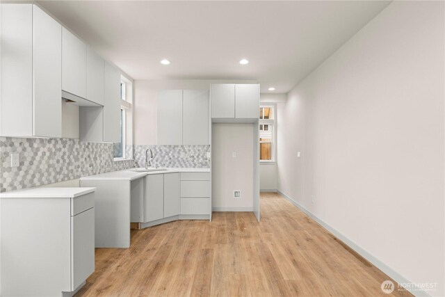 5517A 9th Ave NW, Seattle, WA 98107 - kitchen featuring a sink, light wood finished floors, decorative backsplash, white cabinets, and recessed lighting