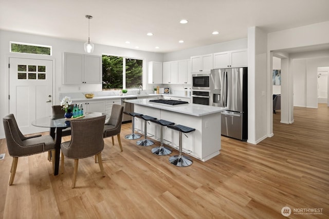 1417 241st Pl SE, Sammamish, WA 98075 - kitchen with appliances with stainless steel finishes, a center island, light countertops, a kitchen bar, and white cabinets