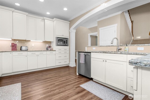 kitchen with appliances with stainless steel finishes, a sink, ornamental molding, white cabinets, and recessed lighting