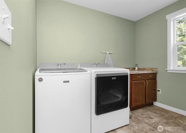washroom featuring cabinet space, washer and dryer, and baseboards