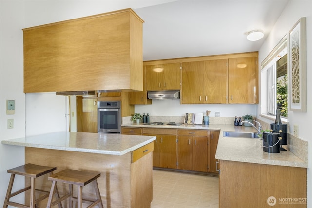 4839 S Mead St, Seattle, WA 98118 - kitchen with stainless steel oven, a sink, under cabinet range hood, light countertops, and a kitchen bar