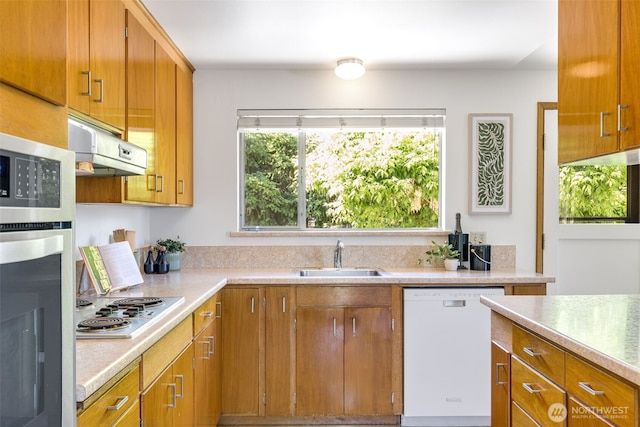 4839 S Mead St, Seattle, WA 98118 - kitchen featuring appliances with stainless steel finishes, a sink, extractor fan, light countertops, and brown cabinetry