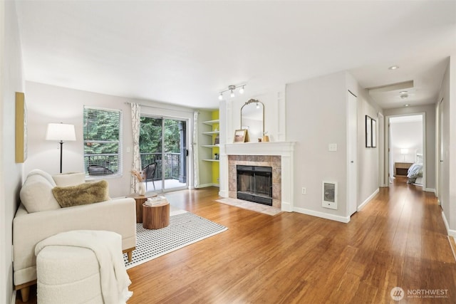 13209 Newcastle Way Unit A308, Newcastle, WA 98059 - living area featuring light wood-type flooring, a tile fireplace, heating unit, built in shelves, and baseboards